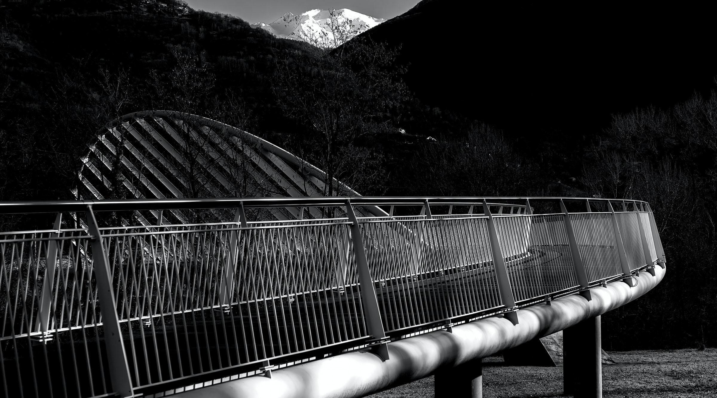 Black and white bridge in the foreground with mountains in the background